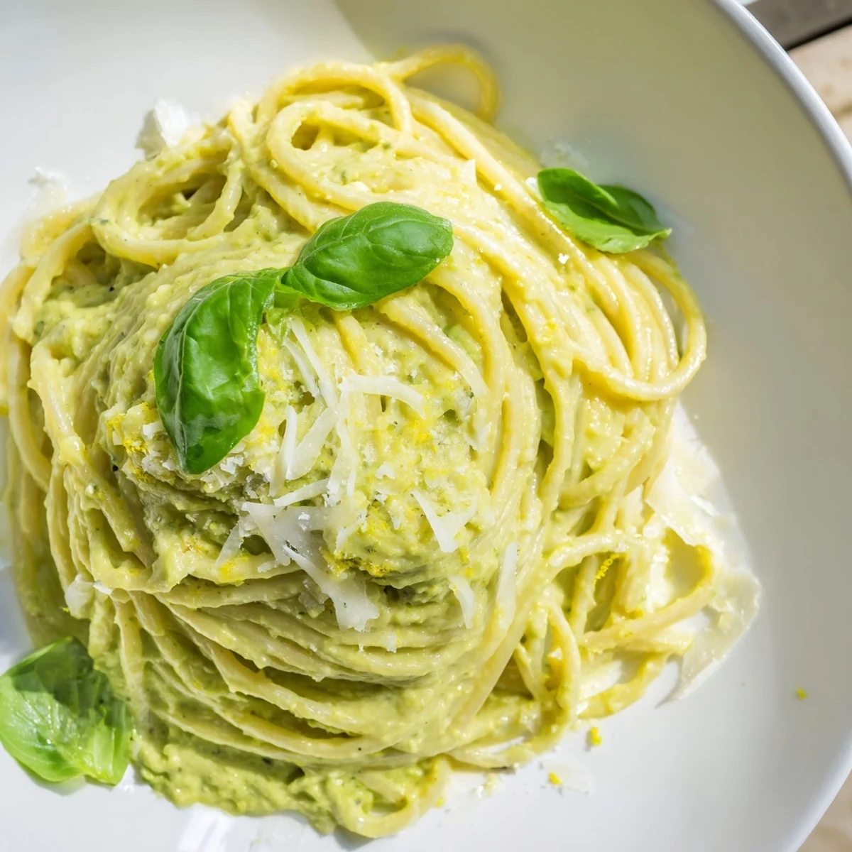 Creamy avocado pasta, a vibrant green dish topped with fresh basil and Parmesan, perfect for dinner.