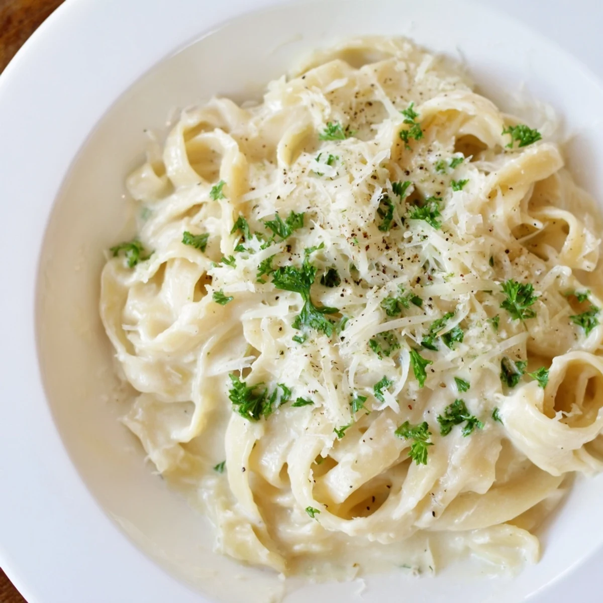 Creamy cottage cheese Alfredo sauce, ready to coat pasta, boasts visible Parmesan and fresh parsley.