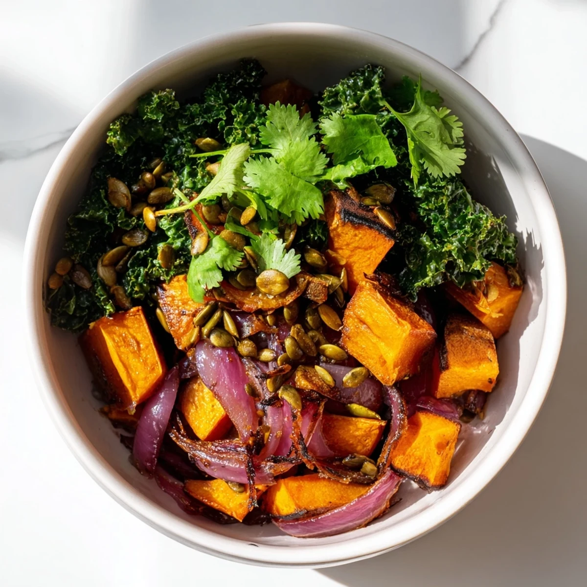 A vibrant bowl of Sweet and Spicy Red Kuri Squash with roasted cubes, kale, and pumpkin seeds.  