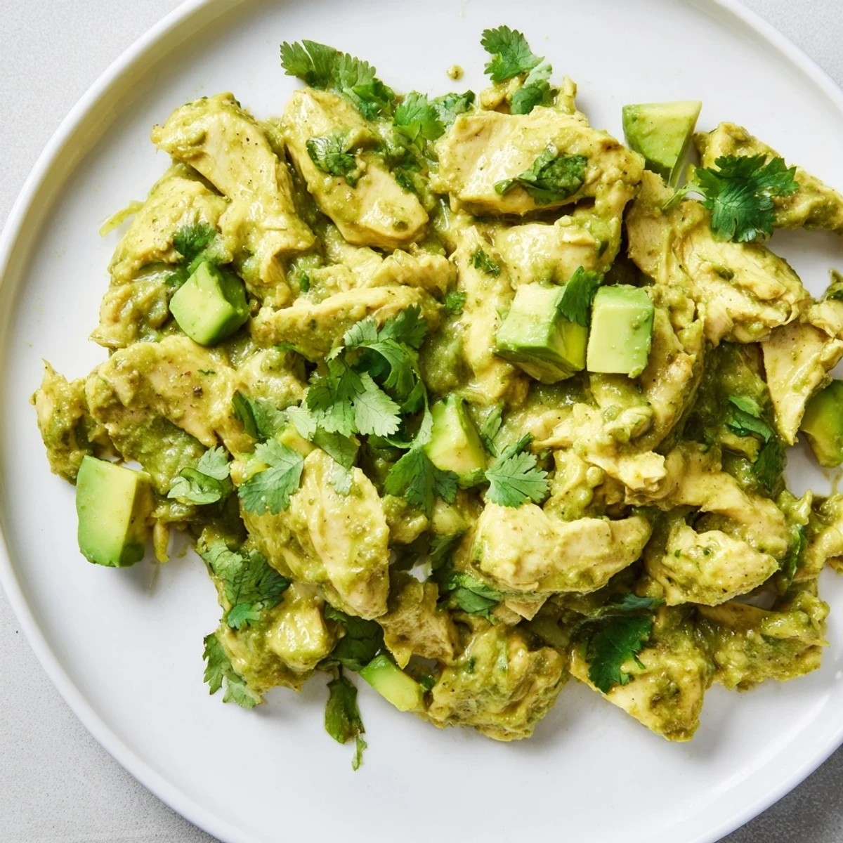 Freshly blended green sauce made from roasted tomatillos, poblano peppers, and garlic coats shredded chicken in this steaming bowl of authentic Chicken Chili Verde, perfect for a family dinner.