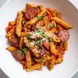 A close-up shot of fiery Spanish Chorizo Pasta, garnished with fresh parsley and cheese.