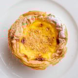 Picture twelve beautifully baked Portuguese egg tarts, nestled in flaky phyllo pastry cups, ready to eat.