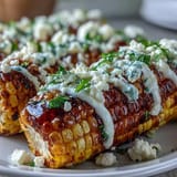 Vibrant elote-style corn on the cob topped with creamy sauce, Cotija cheese, chili powder, and fresh cilantro.