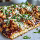 Golden BBQ chicken flatbread pizza loaded with cheese, fresh cilantro, and jalapeños for a zesty flavor.  