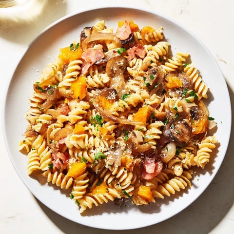 Fusilli with bacon, onions, and mushrooms, a comforting pasta dish with golden, crispy bacon.