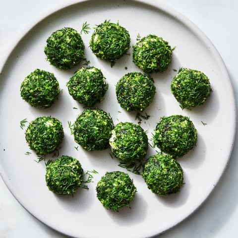 Vibrant close-up of The Mossy Stone appetizer, showing herb-coated creamy goat cheese "stones" ready to serve.