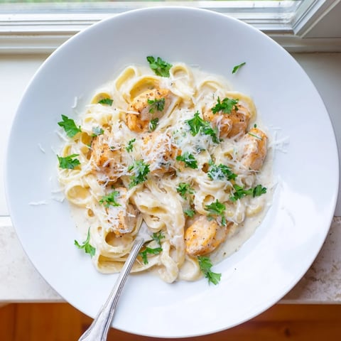 Creamy Skillet Chicken Alfredo with tender chicken strips and fettuccine tossed in a rich Parmesan sauce, garnished with fresh parsley.