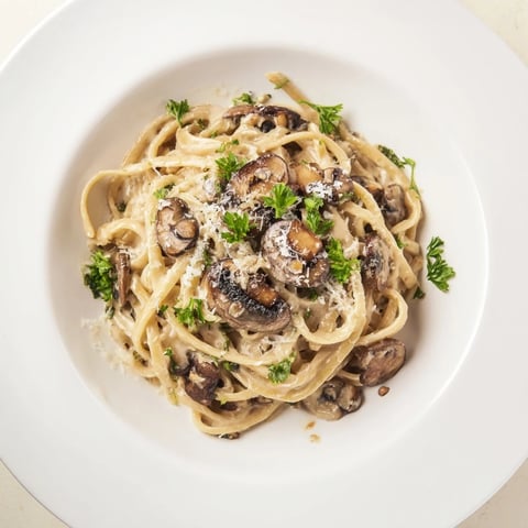 Freshly cooked fettuccine is tossed in a creamy mushroom Alfredo sauce with sautéed cremini mushrooms and fresh parsley garnish.