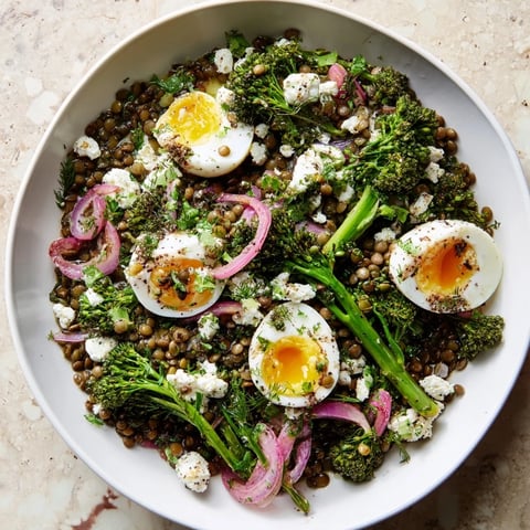 Bright green broccolini and jammy soft-cooked eggs top warm French Lentil Salad with tangy Dijon vinaigrette.