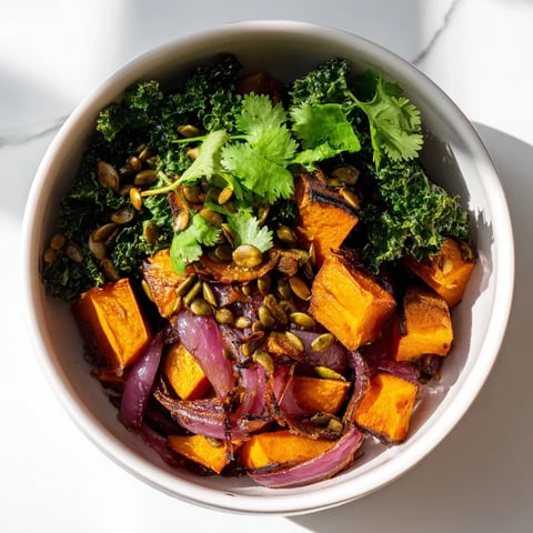 A vibrant bowl of Sweet and Spicy Red Kuri Squash with roasted cubes, kale, and pumpkin seeds.  