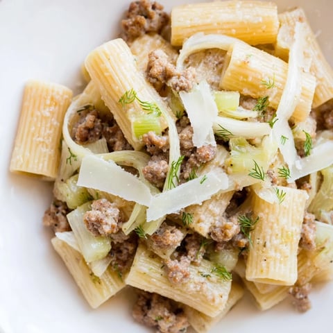 Steam rises from a bowl of Winter Pasta with Sausage and Fennel, featuring golden, al dente penne tossed with browned sausage and tender, caramelized fennel slices.