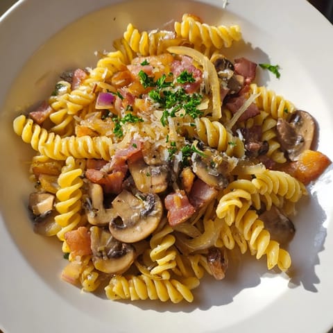 This fusilli with bacon is served hot, showcasing the perfectly mixed ingredients and textures.