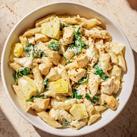 This Creamy Spinach Artichoke Protein Pasta Skillet showcases a close-up of tender pasta and creamy sauce, ready to serve.