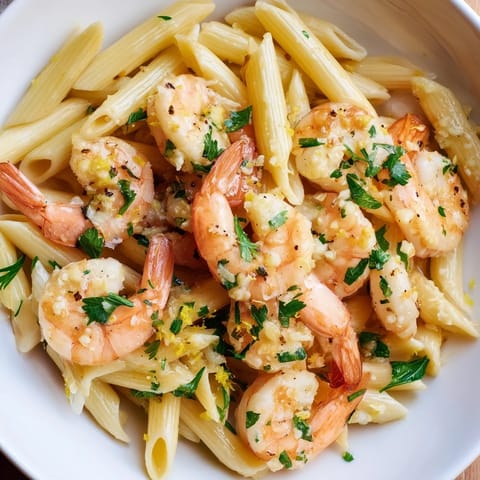 A steaming bowl of garlic shrimp penne, garnished with fresh parsley and Parmesan cheese.