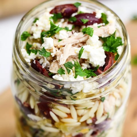 Freshly prepared Greek Pasta Chicken Salad Jars featuring colorful veggies and herbs for grab-and-go lunches.  