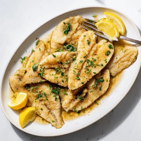 Flounder meunière served hot over pasta, with a wedge of lemon and chopped parsley.  