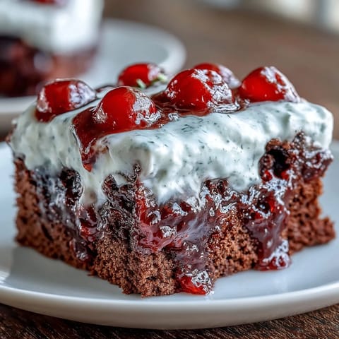 Cherry Cola Jello Poke Cake with whipped cream and cherry garnish.