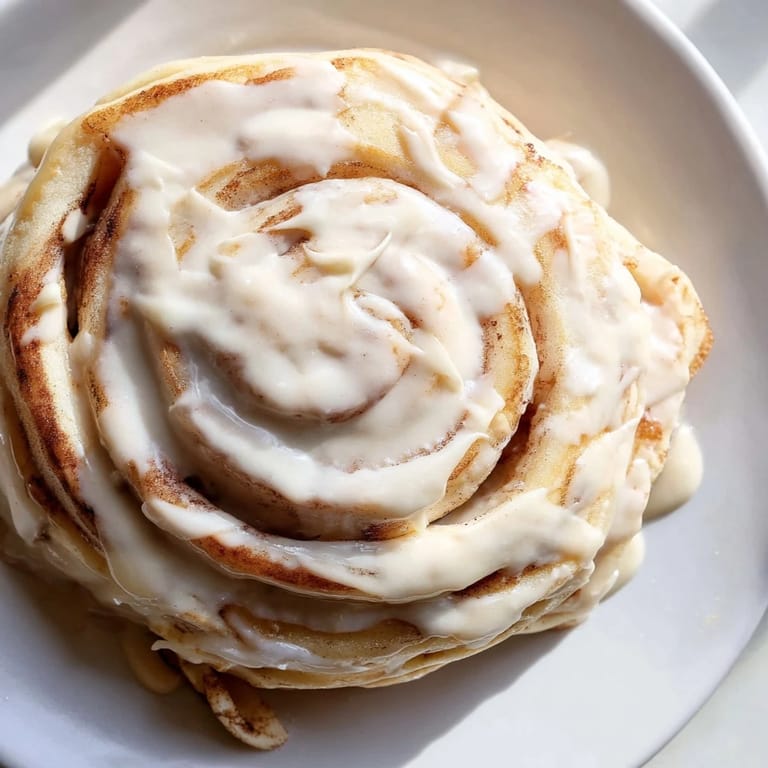 Warm, fluffy stack of Cinnamon Roll Pancakes with a visible cinnamon swirl, perfect for brunch.