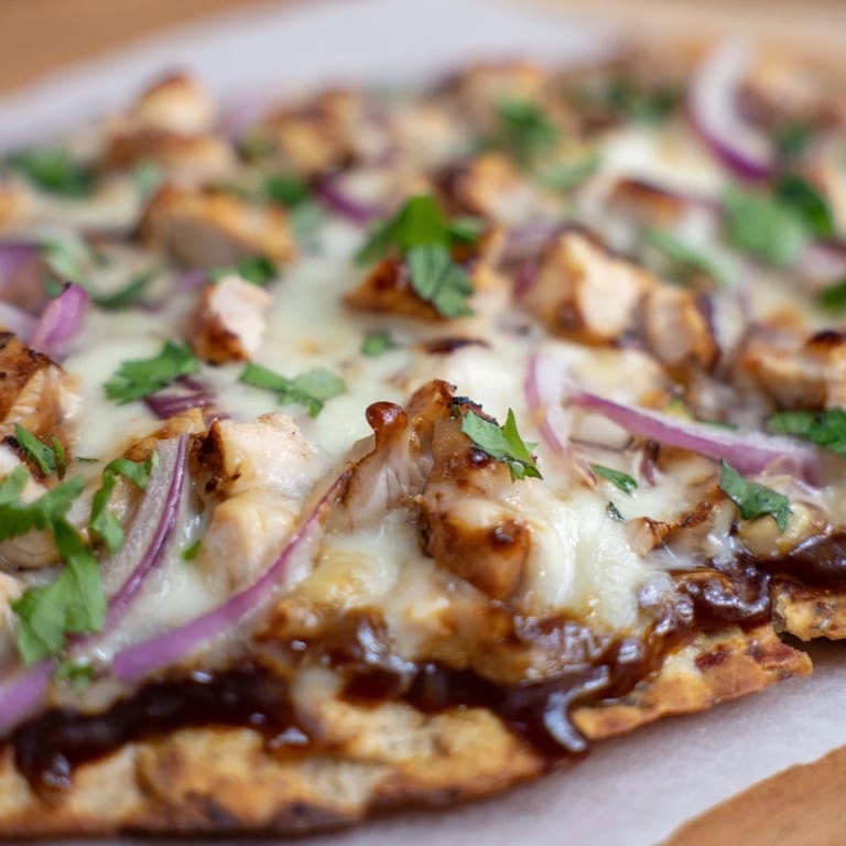 Slice of savory BBQ Chicken Flatbread topped with tender grilled chicken and sweet red onion
