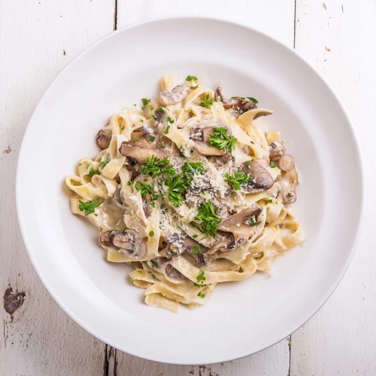 Plate of homemade creamy mushroom Alfredo, served hot with extra Parmesan and chopped parsley for a comforting vegetarian dinner.