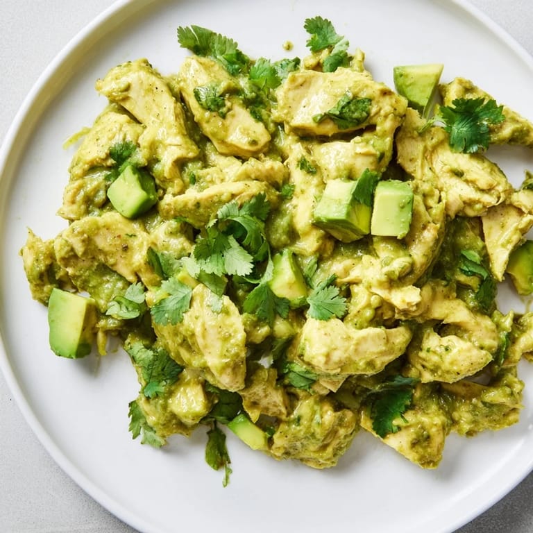 Freshly blended green sauce made from roasted tomatillos, poblano peppers, and garlic coats shredded chicken in this steaming bowl of authentic Chicken Chili Verde, perfect for a family dinner.