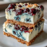 Creamy no-bake lemon blueberry cheesecake bars with bright swirls.